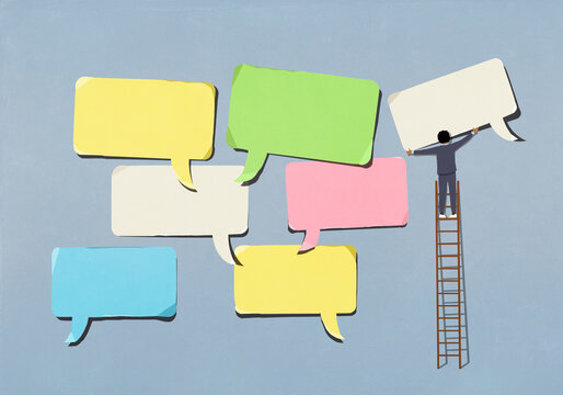 Businessman on ladder arranging large, multicolored speech bubbles on blue background
