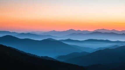 Fototapeta premium A misty sunset with layers of mountains fading into the distance.
