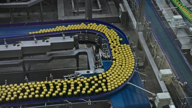 Modern automated beer factory with canning production line. Hundreds aluminum cans move fast conveyor belt clean industrial facility. High-tech beverage manufacturing process.