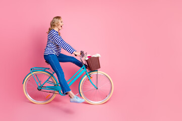 Young stylish woman on a blue bike against a pink background that exudes cheerful and happy vibes...