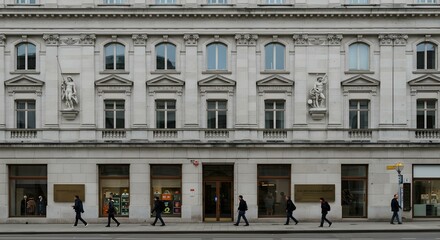 Fototapeta premium White neoclassical city building facade with uniform windows and retail stores at base.