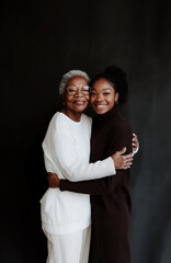 Grandmother and granddaughter share a warm embrace against a neutral backdrop