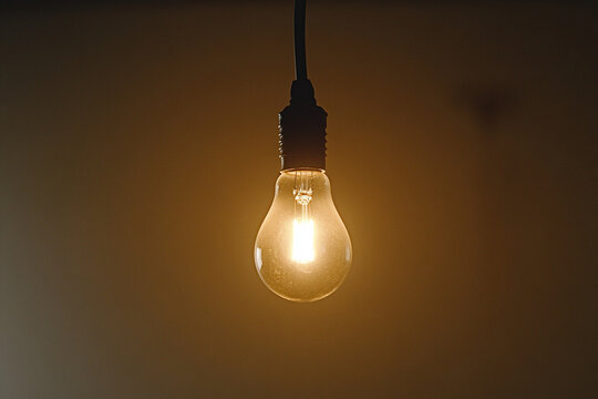 Faintly glowing light bulb casting a warm ambiance in a dimly lit space, illustrating chaos and mood