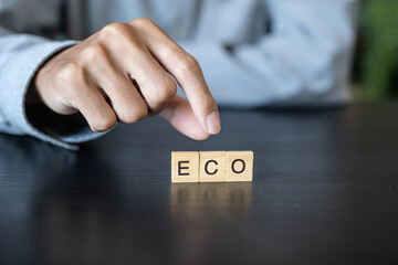 ECO concept. Business man hand holding wooden cube words ECO on a wood block