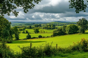 Obraz premium Valley view in Kilkenny park showcasing lush green landscape and dramatic cloud formations, A beautiful valley in the park Green area Kilkenny Ireland