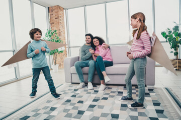 Fototapeta premium Happy family bonding indoors with children playing creatively in a well lit modern living room during a joyful daytime moment
