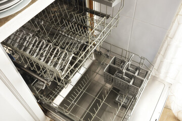 Empty and open dishwasher with racks removed in kitchen