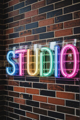 Obraz premium Vibrant Neon 'STUDIO' Sign Glowing Against Rustic Brick Wall in Creative Workspace