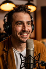 Engaging Podcast Host with Headphones Smiling at Microphone in Warm Studio Lighting