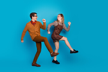 Dynamic young couple posing against blue background showcasing vibrant retro fashion