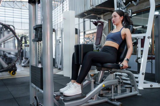 Young sportswoman exercising inner thigh muscles on a fitness machine in a modern gym, embodying commitment to health and fitness while enhancing her strength and athleticism
