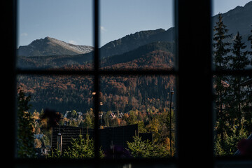 Beautiful view from the window to the forest and mountains at sunset. Autumn mountain landscape in Zakopane, Poland.