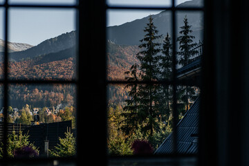 Horizontal window frame view to the chalet, forest and mountains at sunset. Autumn mountain landscape in Zakopane, Poland.