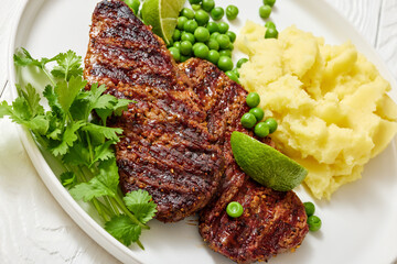 grilled beef cutlets with potato mash, green peas