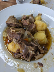 A close-up shot reveals a plate filled with a flavorful beef stew, potatoes and vegetables.