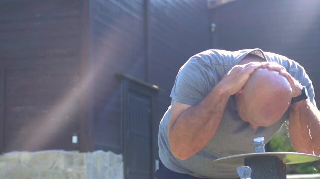 Slow motion. A man refreshes himself with fresh water in a fountain on a hot summer day in the park