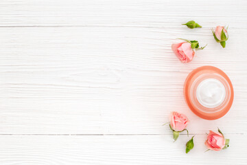 Homemade organic cosmetic with roses essential oil. Face cream with flowers and petals, top view