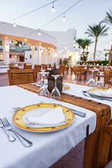 Elegant outdoor dining setup with decorative tableware in a warm evening atmosphere by a resort