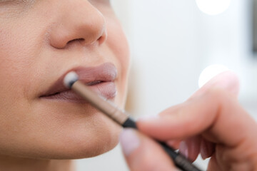 close up Professional lips Makeup, beautician applies lipstick, Beautiful woman face, Hand of...