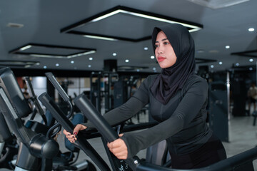 Muslim Woman in Sports Hijab Using Treadmill in Modern Gym