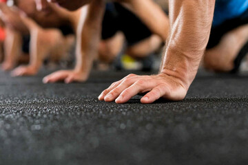 Man performing push-ups on a mat in a bustling gym during a fitness class