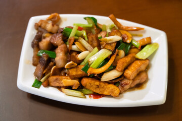 Hakka-style stir-fried squid and pork, Tofu, and scallions on white plate.