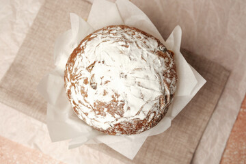 Traditional Easter cake with powdered sugar on soft beige linen background. Rustic homemade dessert for spring holiday