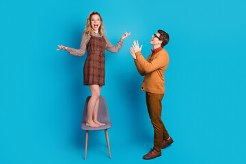 Young Couple in Casual Attire on Blue Background Sharing Joyful Emotions