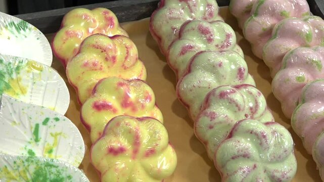Colorful floral-shaped bath salt bombs are neatly arranged in rows, wrapped in plastic, ready for sale in a cosmetic or wellness shop.
