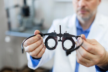 Professional man optometrist holding messbrille, working in ophthalmology clinic office, stretching...