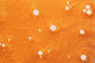 Golden cosmetic shimmer liquid lotion gel illuminator texture smudge swatch on white background