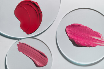 Cosmetic texture smudge fuchsia liquid lipstick. Swatches isolated on grey circle glass 