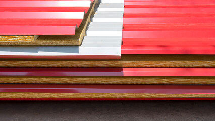Pile of red corrugated metal sheet roof with PU foam insulation in wood pattern stacked on the...