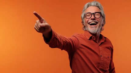 Fototapeta premium Smiling older man dressed in orange shirt pointing with enthusiasm against bright orange background