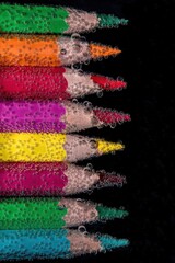 colored pencils underwater with air bubbles on black background