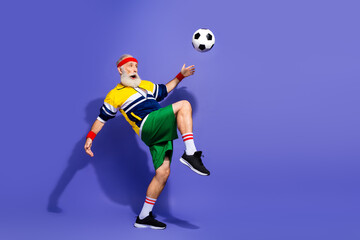 Obraz premium Elderly gentleman playing soccer in retro sportswear performing athletic activity on a vibrant background showcasing fitness lifestyle