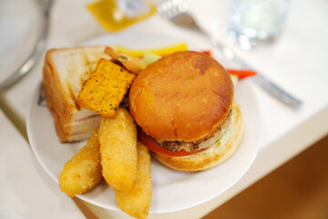 Top view of plate with burger, toast, crackers, vegetables and nuggets.