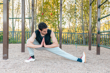Man performing Cossack squat stretch in outdoor calisthenics park for hip mobility, balance, and leg flexibility, wearing fitness apparel on gravel surface
