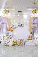 Round white background decorated with balloons and cake table. 