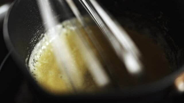 Female chef preparing bechamel sauce, stirring in bowl.
