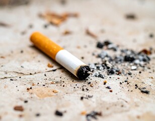 A close-up of a cigarette discarded on a concrete surface, surrounded by ash and debris, highlighting the impact of smoking.