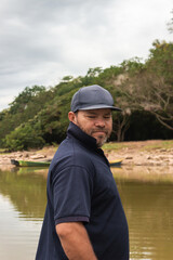 Fototapeta premium Portrait of a man wearing a black cap casually looking down from a canoe in Yaguara, Huila, Colombia. Colombian people concept