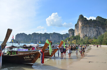 Worker guide local people sailing wooden long tail boat stop for send receive thai and foreign traveler travel visit rest relax on sand beach at Ao Nang Railay bay on April 23, 2011 in Krabi, Thailand