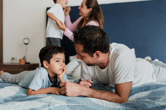 latin family father playing with children on bed at home in Mexico Latin America, hispanic people in pajamas