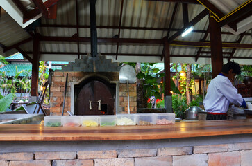 Fototapeta premium Thai men chef people use firewood stove old style cooking bread pizza at restaurant serve travelers guest customer eat drink at restaurant shop at resort hotel on April 23, 2011 in Krabi, Thailand