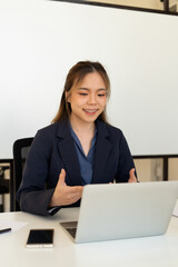 Businesswoman sitting at desk on couch in workplace or at home working on laptop and analyzing data on charts and graphs and writing on papers to make business plan and strategies for company.