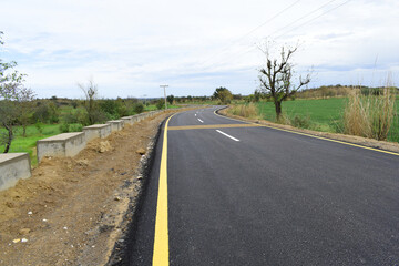 Newly constructed asphalt road with clipping path, asphalt highway road with sky clouds natural landscape, asphalt road passing through agricultural fields under blue sky in Chakwal, Punjab, Pakistan