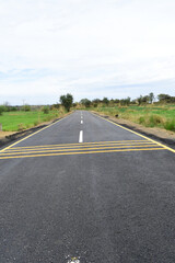 Newly constructed asphalt road with clipping path, asphalt highway road with sky clouds natural landscape, asphalt road passing through agricultural fields under blue sky in Chakwal, Punjab, Pakistan