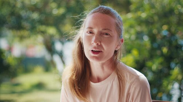 Caucasian young adult woman speaks on camera during interview with naturally blurred background