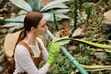 Young woman nurtures plants in a vibrant greenhouse overflowing with greenery